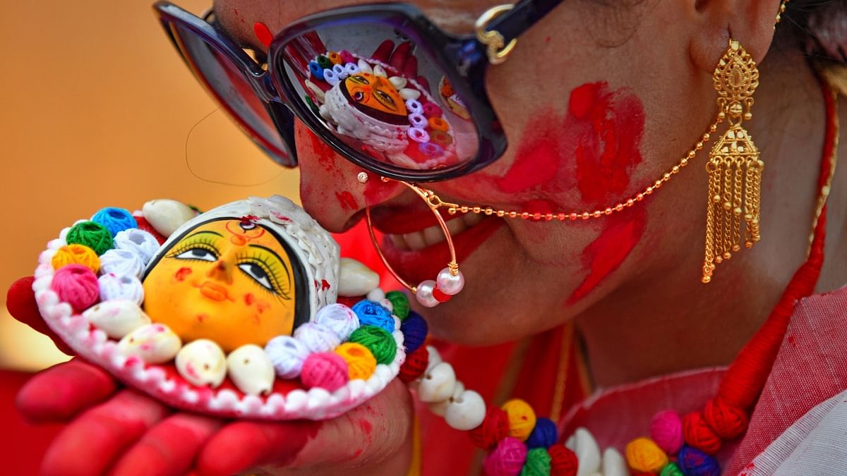 A woman poses for photos with her jewellery inspired by Goddess Durga while participating in 'Sindoor Khela' on the last day of Durga Puja festival celebrations, in Chandigarh. Credit: PTI Photo