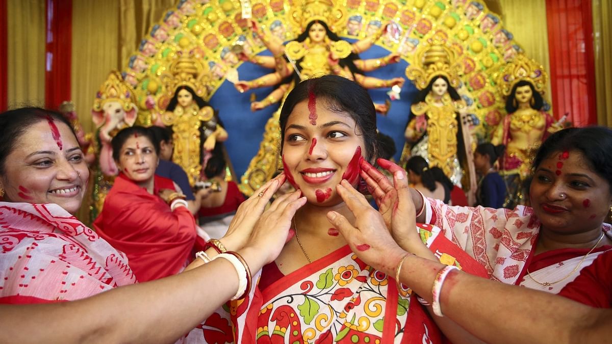 Married women apply vermillion on each other as they participate in 'Sindoor Khela' on the last day of Durga Puja festival celebrations, in Agartala. Credit: PTI Photo