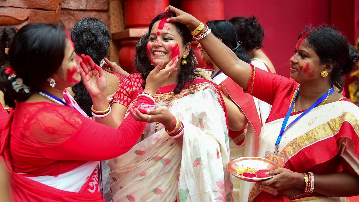 Married women apply vermillion on each other as they participate in 'Sindoor Khela' on the last day of Durga Puja festival celebrations, in Mumbai. Credit: PTI Photo