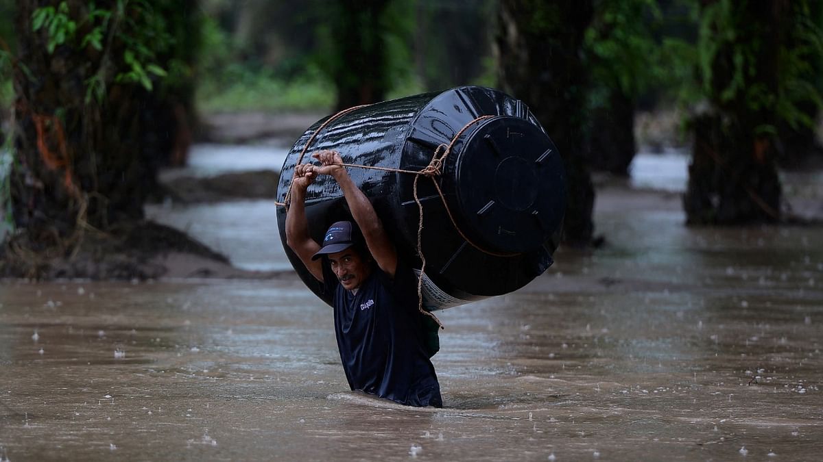 A man carries an empty water tank through a flooded area after the impact of the tropical storm Julia, in Progreso, Honduras. Credit: Reuters Photo