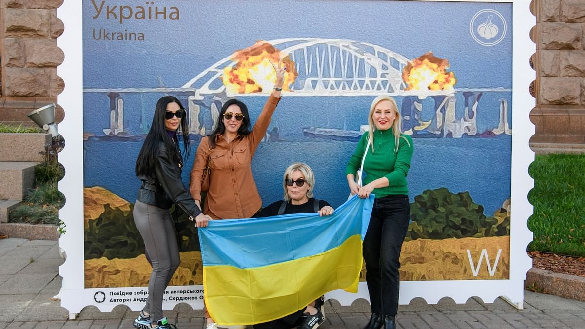 Women were seen posing with the Ukrainian national flag next to the artwork depicting Kerch bridge on fire, amid Russia's attack on Ukraine. Credit: Reuters Photo