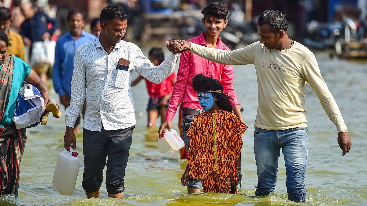 People in Allahabad's Sangam wade through a flooded path as they struggle to move in the city. Credit: AFP Photo