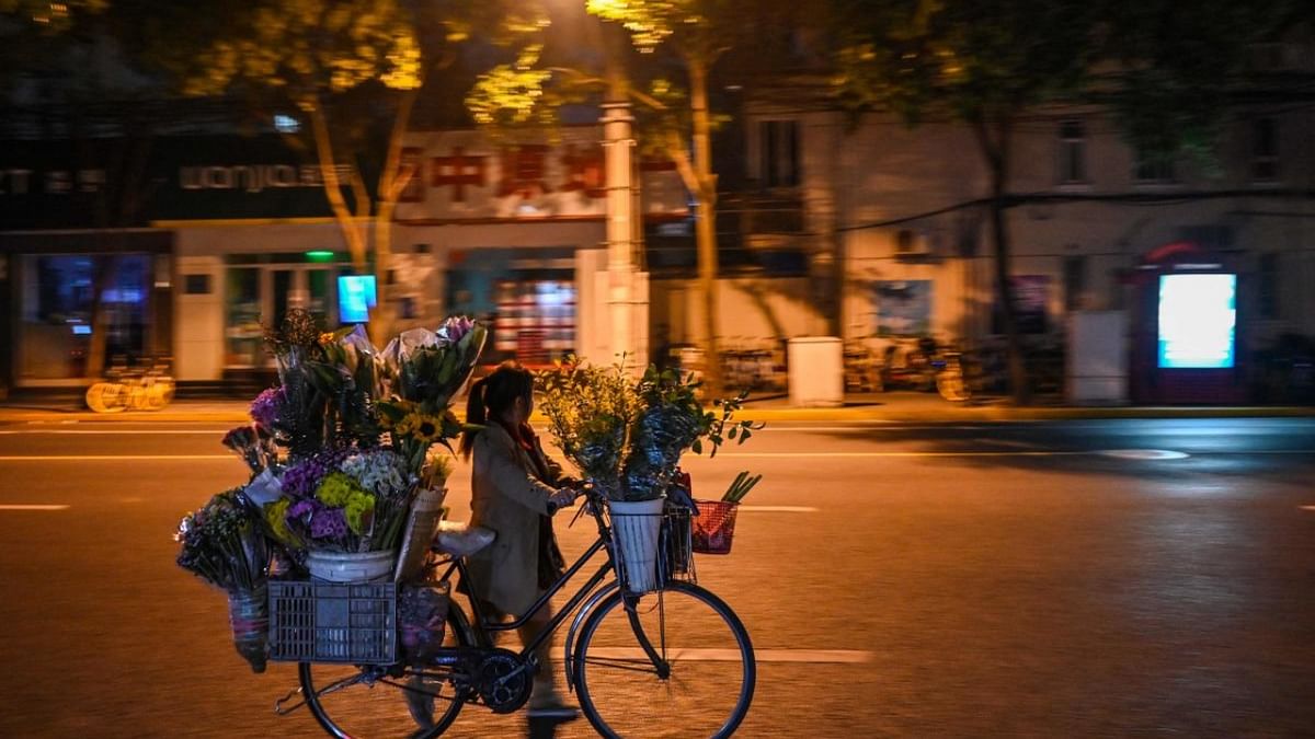 A flowers seller walks on a street during the night in the Jing'an district in Shanghai. Credit: AFP Photo
