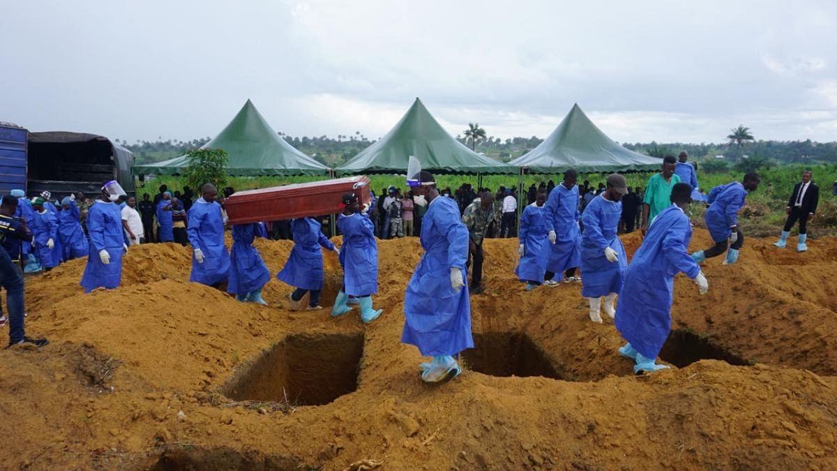 Health workers carry a coffin during the mass burial of twenty-seven protestors and six police officers at the Bolima cemetery in the Waterloo district in Freetown. Credit: AFP Photo