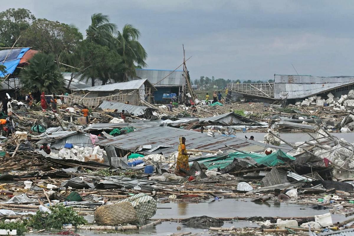 Residents search for their belongings amid the debis of their collapsed huts after the cyclone Sitrang hits in Chittagong. At least 35 people have died after a cyclone slammed into Bangladesh, forcing the evacuation of around a million people from their homes, officials said. Credit: AFP Photo
