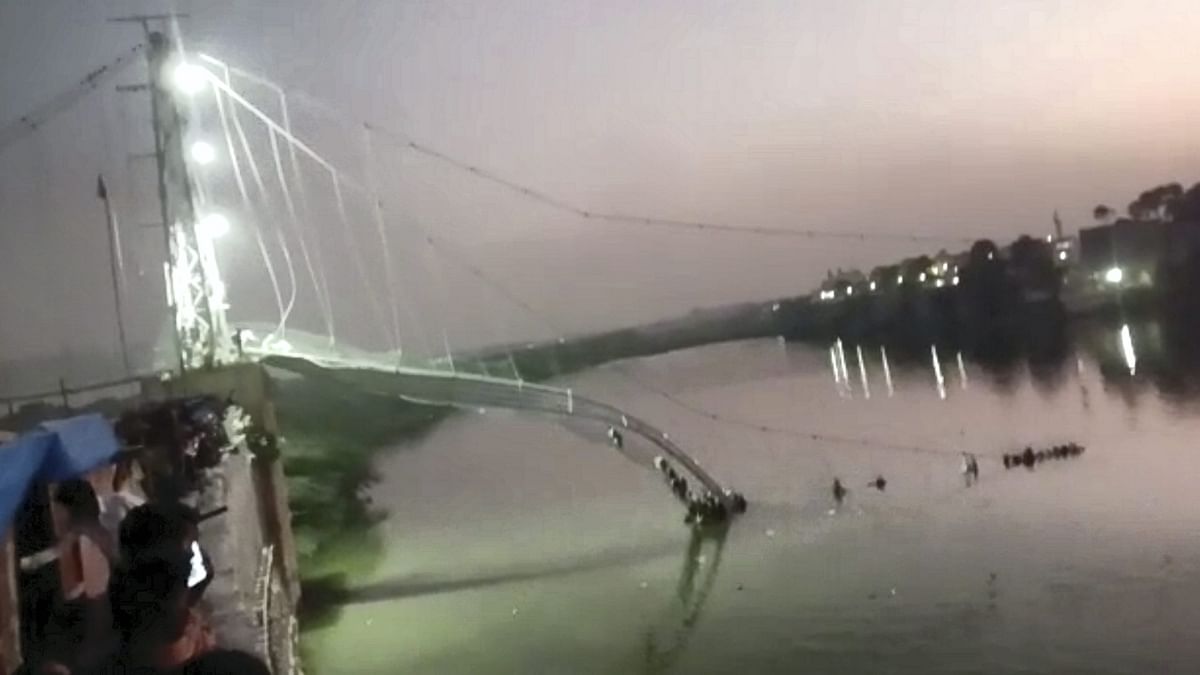 After the collapse, all that remained of the bridge was part of the metal carriageway hanging down from one end into the river and its thick cables snapped in places. Credit: PTI Photo