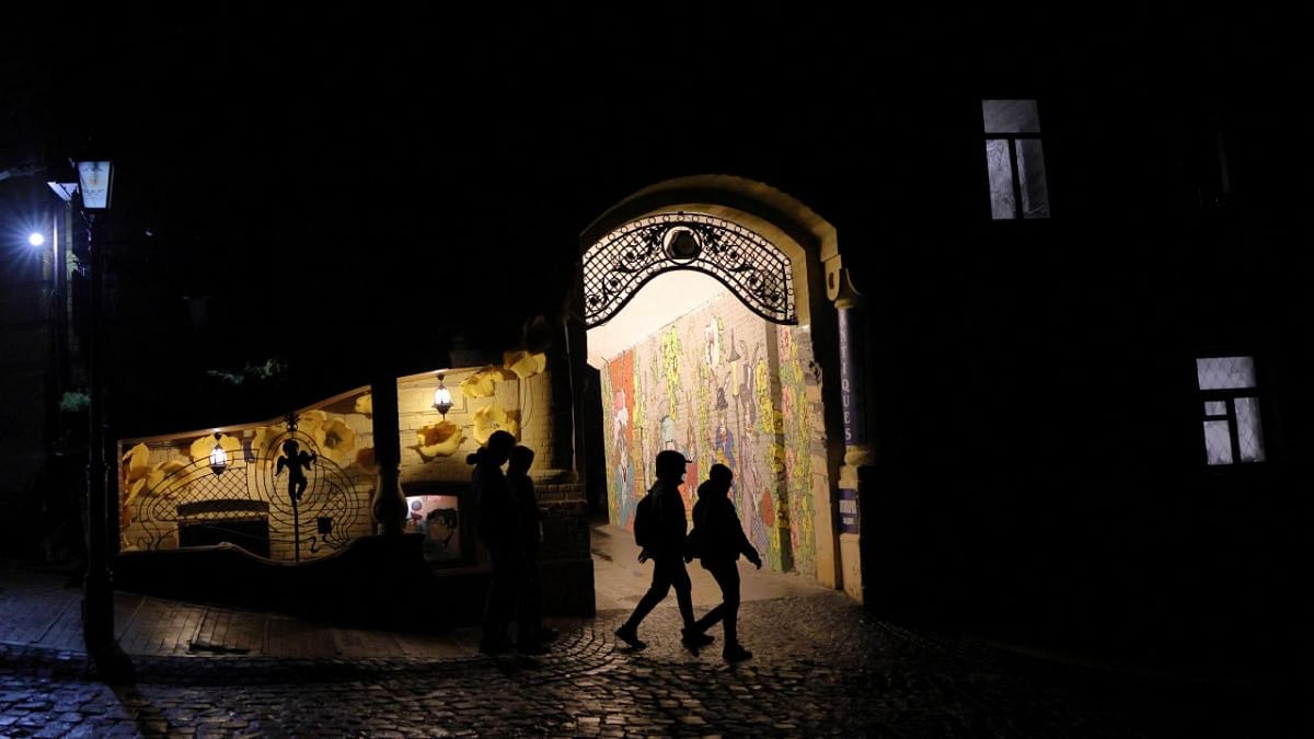 People walk on a dark street, as Russia's attack on Ukraine continues, in the old town of Kyiv. Credit: Reuters photo