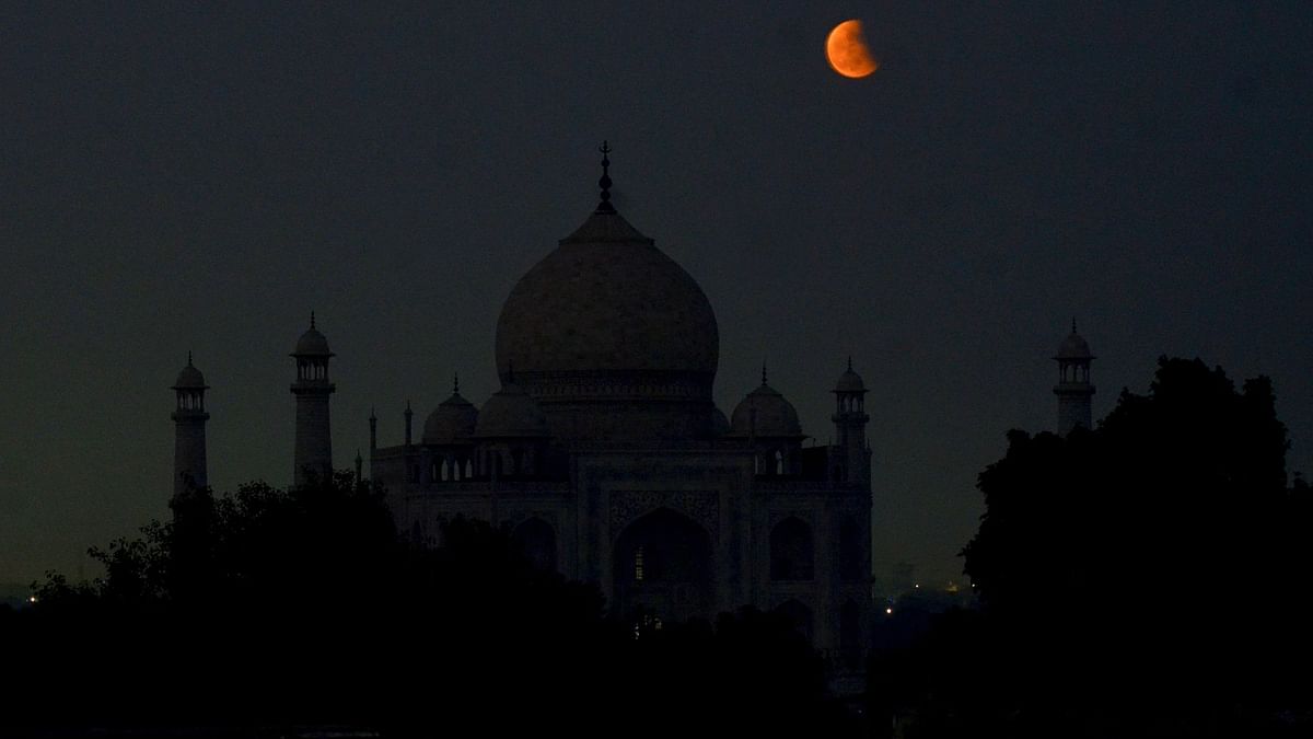 Moon partially covered by the earth's shadow during lunar eclipse, seen behind the Taj Mahal in Agra. Credit: PTI Photo