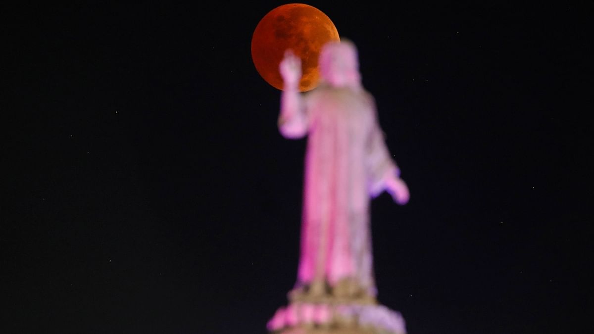 The moon is seen behind a statue during the lunar eclipse in San Salvador, El Salvador. Credit: Reuters Photo