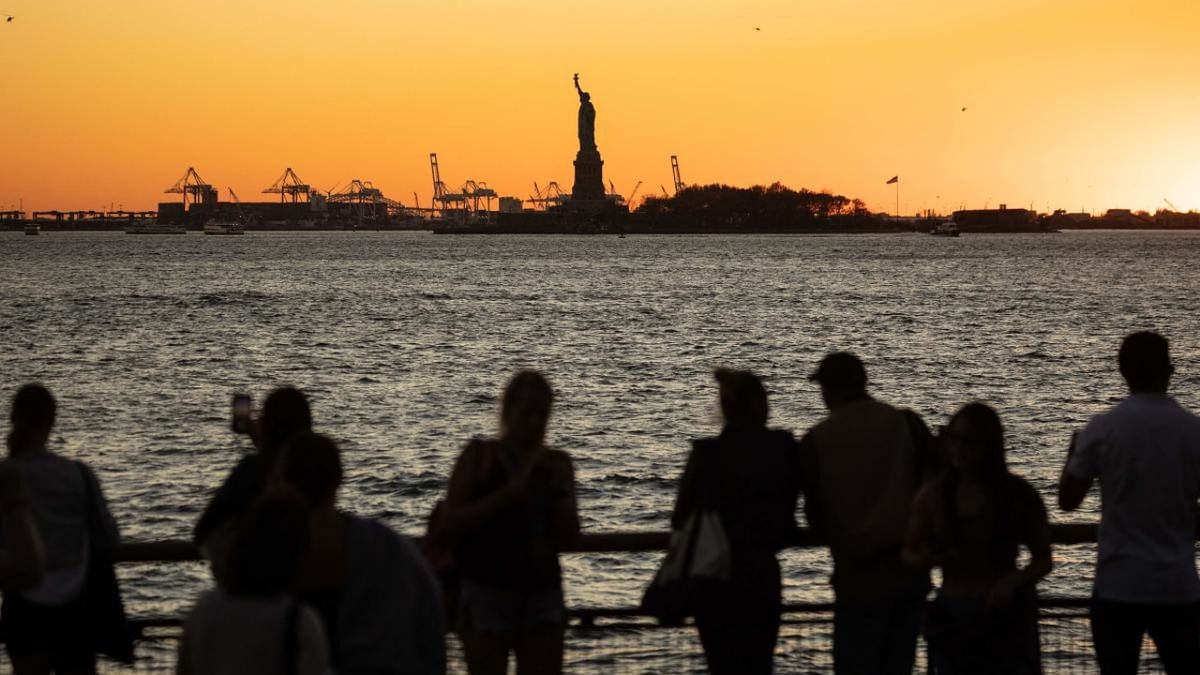People watch the sun set behind the Statue of Liberty on November 7, 2022 in New York. Credit: AFP Photo