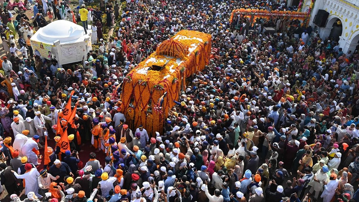 Sikh devotees gather around a bus carrying the Guru Granth Sahib (Sikhism holy book) during a religious procession on the occasion of the birth anniversary of Guru Nanak Dev, the founder of Sikhism, in Nankana Sahib on November 8, 2022. Credit: AFP Photo