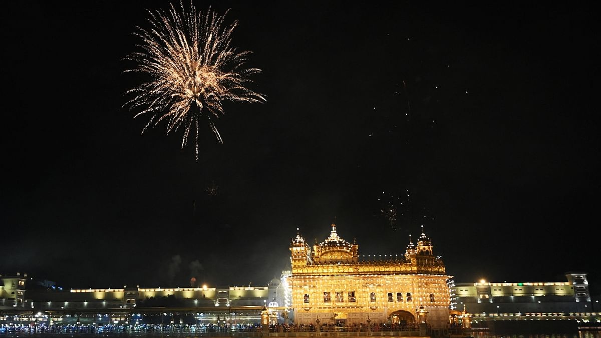 Devotees watch a fireworks display at the illuminated Golden Temple on the occasion of the birth anniversary of Guru Nanak Dev in Amritsar. Credit: AFP Photo