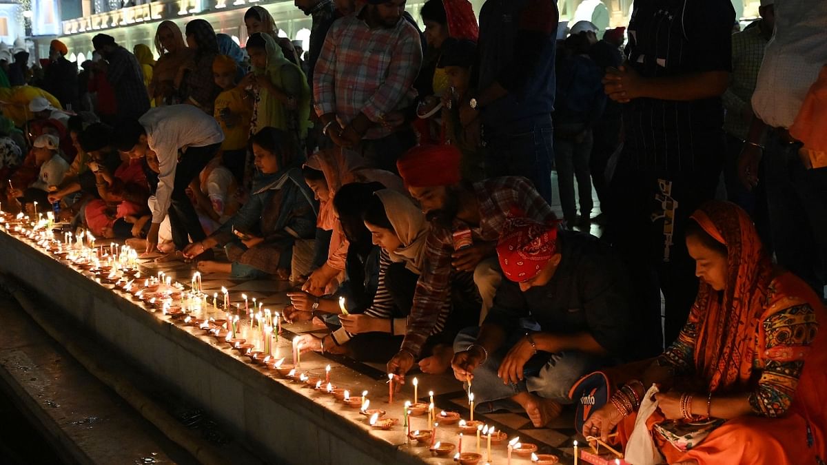 Devotees light candles at the illuminated Golden Temple on the occasion of the birth anniversary of Guru Nanak Dev in Amritsar. Credit: AFP Photo