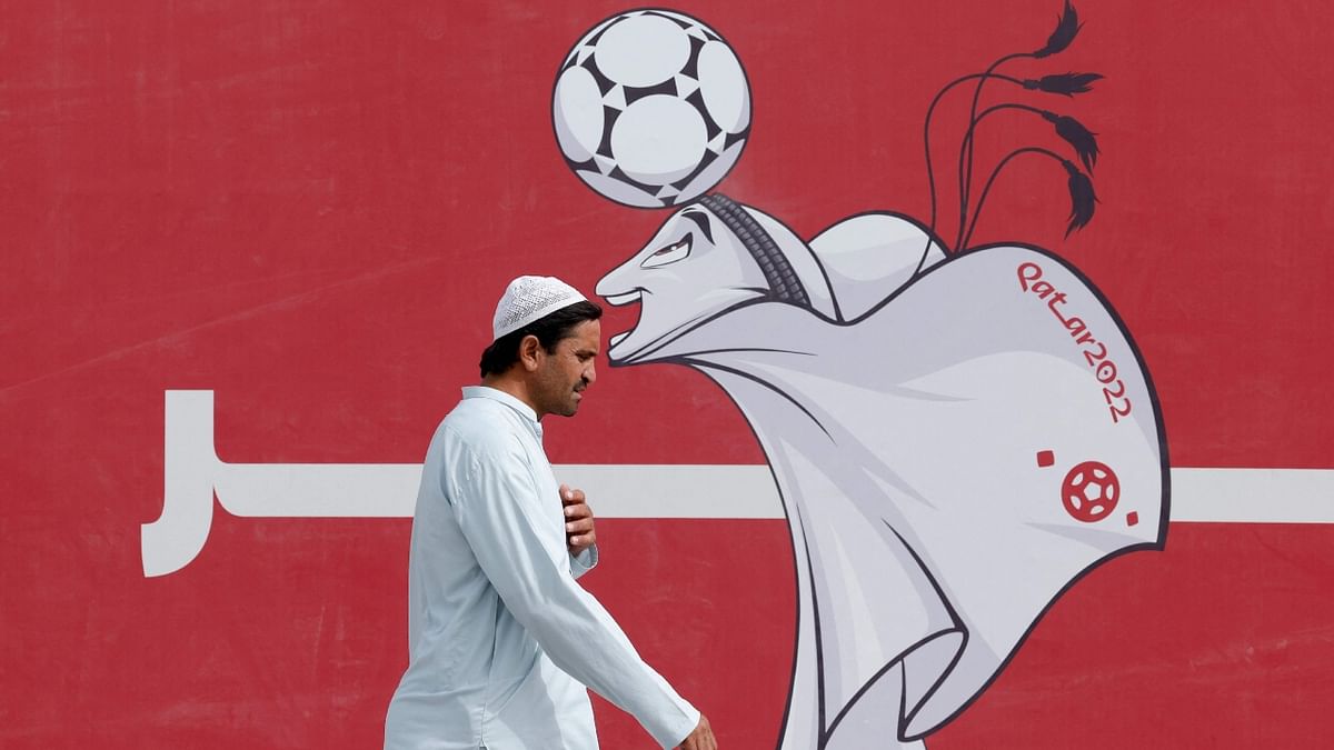 A man walks past a poster of the Qatar 2022 mascot La'eeb in Doha on November 9, 2022, ahead of the Qatar 2022 FIFA World Cup football tournament. Credit: AFP Photo