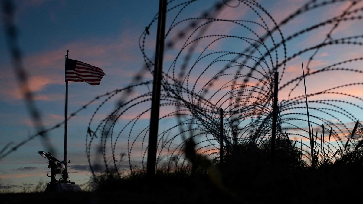 The American flag flies over barbed wire fence next to the Rio Grande River in Eagle Pass, Texas on November 8, 2022. Credit: AFP Photo