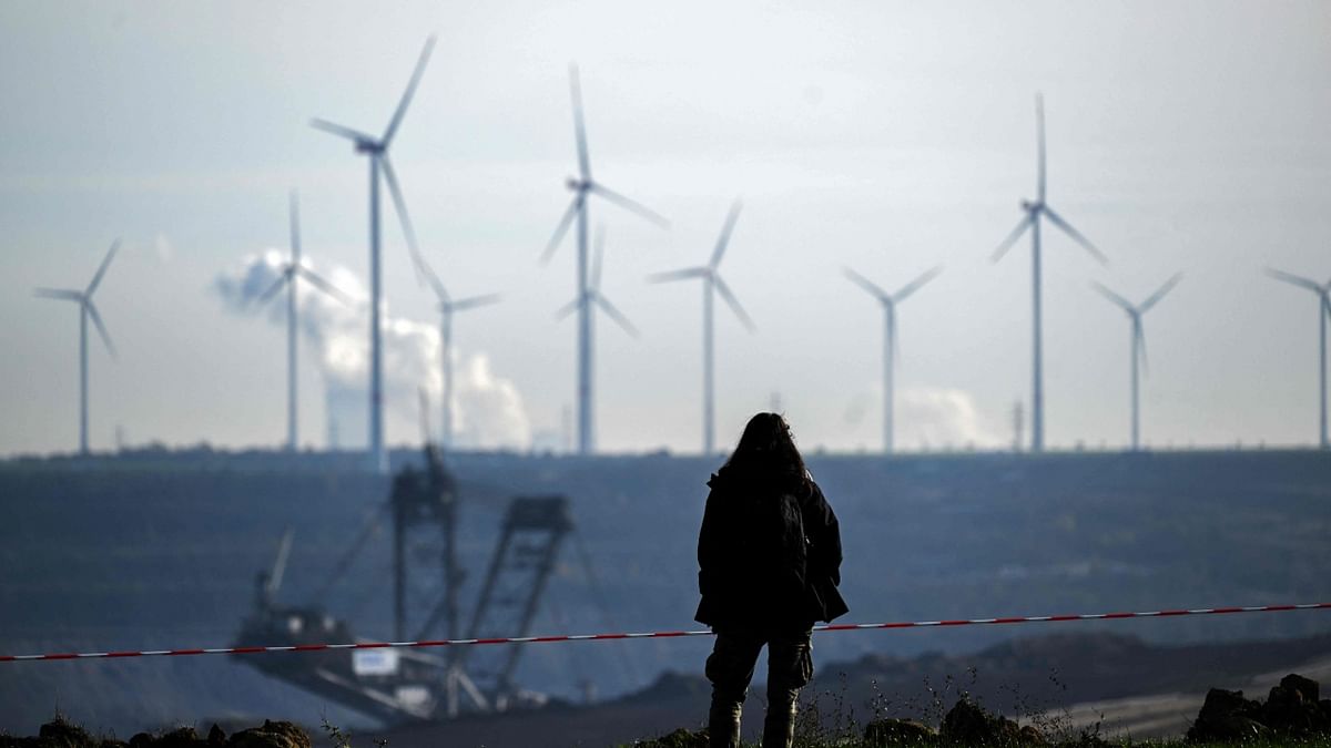 A woman stands on the edge of the Garzweiler lignite open cast mine near Luetzerath, western Germany, on November 12, 2022, as in background can be seen wind engines. Credit: AFP Photo