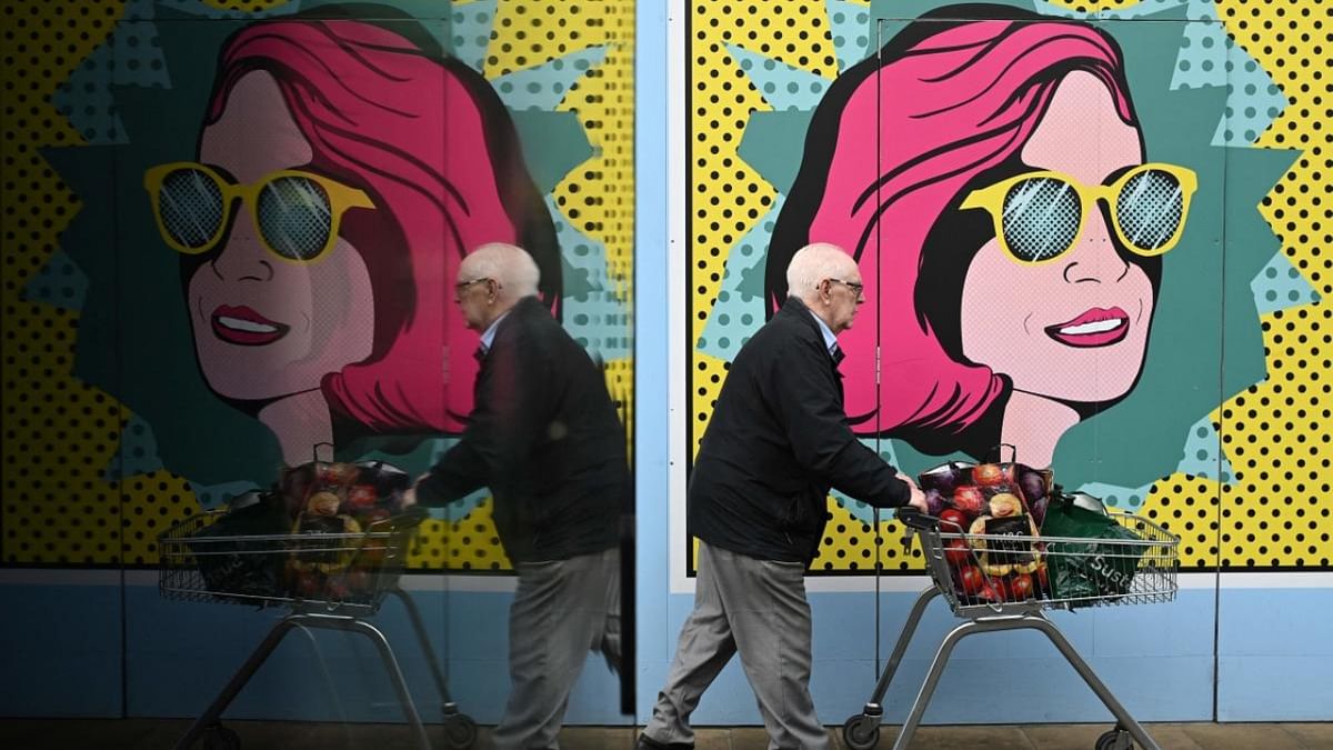 A man pushes a cart past colourful boards put up at a closed shop in Chester on November 17, 2022. Credit: AFP Photo