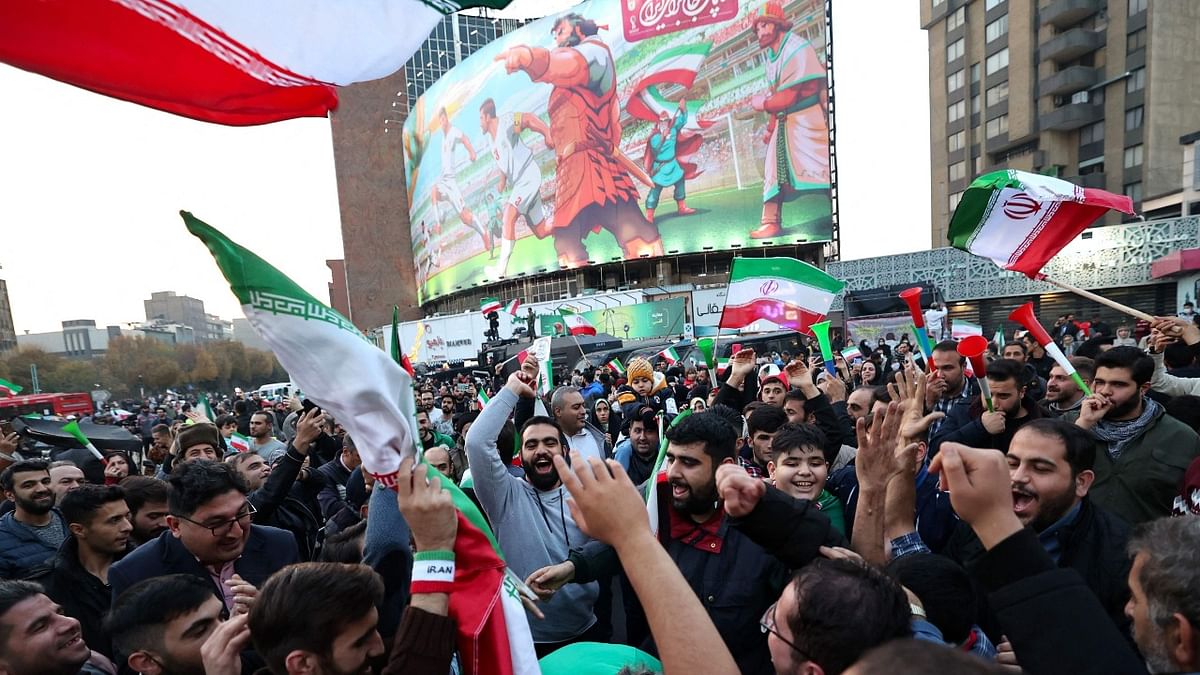 Iranian fans raise national flags as they celebrate their football team's win against Wales during the Qatar 2022 World Cup, in the capital Tehran. Credit: AFP Photo