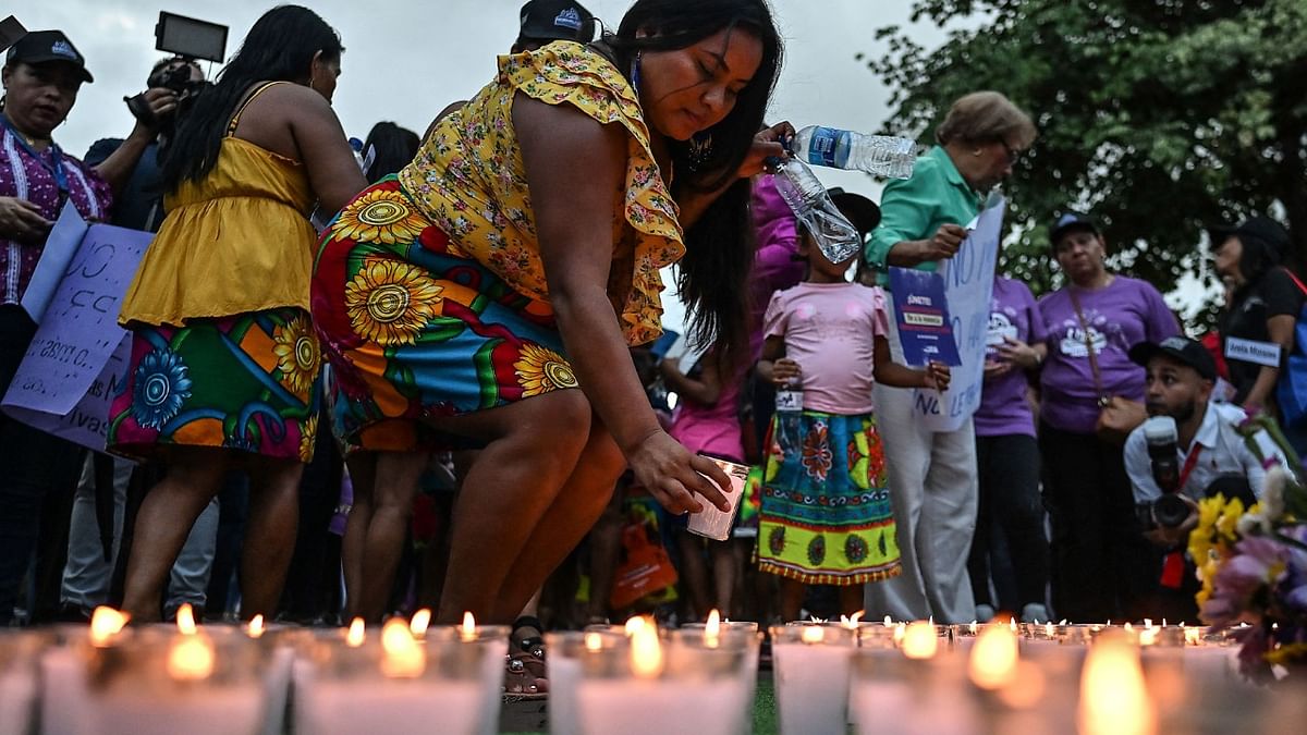 A woman places a lit candle during a demonstration to demand justice for the victims of femicide in Panama City. Credit: AFP Photo