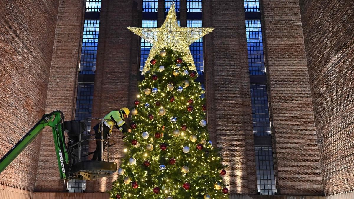 A worker on a cherry-picker makes adjustments to a giant Christmas tree outside Battersea Power Station in south London. Credit: AFP Photo