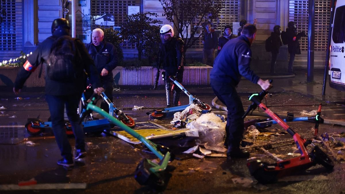 Police officers move damaged scooters during a clash in Brussels. Violence broke out in Brussels after Morocco's victory over Belgium at the World Cup, with