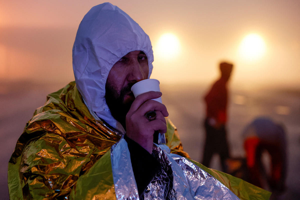 A migrant from Afghanistan warms himself in an emergency blanket after being rescued by a French maritime protection vessel as the boat he was travelling in with 60 other migrants began to take water in the English Channel, in an attempt to reach Britain. Credit: Reuters Photo