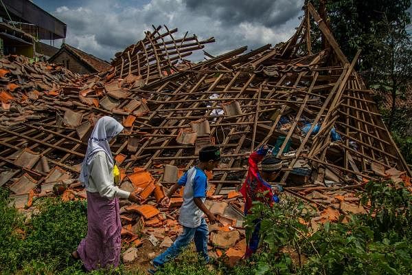 Children of earthquake victims walk past a collapsed house at Cugenang village in Cianjur, West Java. Credit: AFP Photo