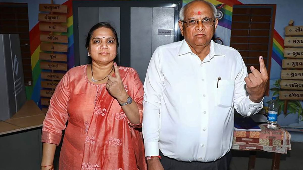 Gujarat Chief Minister Bhupendra Patel and his wife show their inked finger after casting their vote at a polling booth during the second and final phase of Gujarat Assembly elections in Ahmedabad. Credit: Twitter/@Bhupendrapbjp