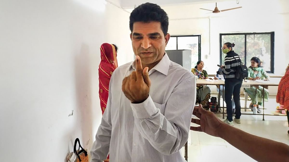 AAP's chief ministerial candidate Isudan Gadhvi shows his inked finger after casting his vote at a polling booth during the second and final phase of Gujarat Assembly elections in Ahmedabad. Credit: PTI Photo