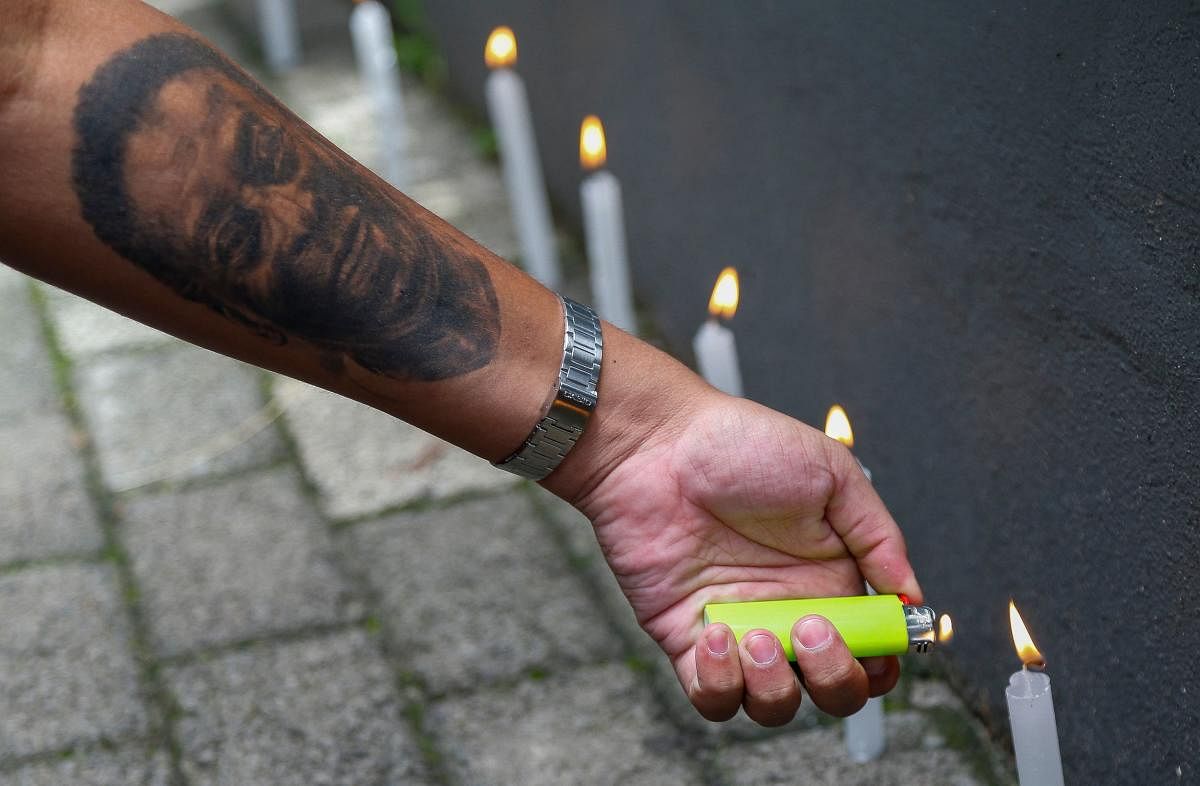 A fan of Santos with his arm tattooed with an image of Brazilian football legend Pele lights candles during a vigil outside the Albert Einstein Israelite Hospital entrance, where the former player is hospitalized in Sao Paulo, Brazil. Credit: AFP Photo