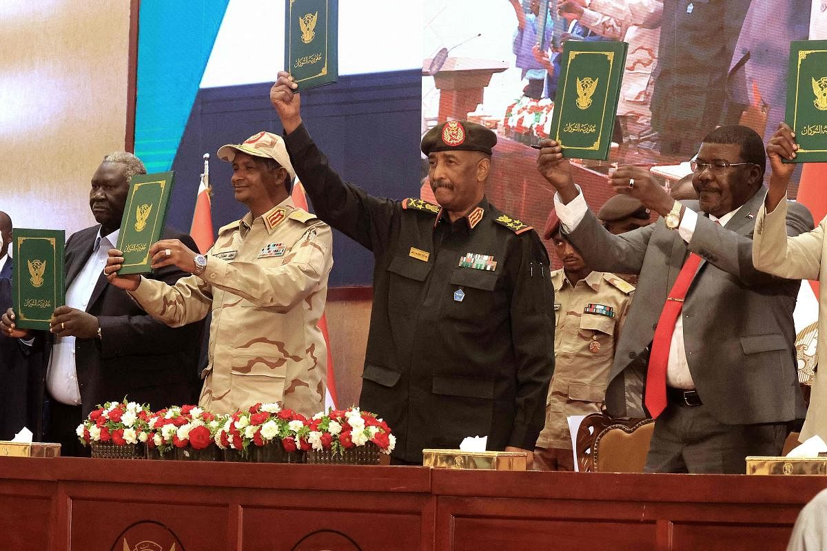 Sudan's Army chief Abdel Fattah al-Burhan (C R) and paramilitary commander Mohamed Hamdan Dagalo (C L) lift documents alongside civilian leaders following the signing of an initial deal aimed at ending a deep crisis caused by last year's military coup. Credit: AFP Photo