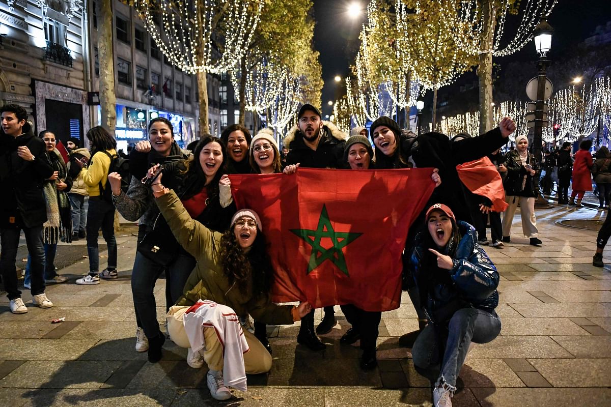 Morocco supporters cheer with a national flag as they celebrate their national team's victory after the Qatar 2022 World Cup football match between Morocco and Spain. Credit: AFP Photo.