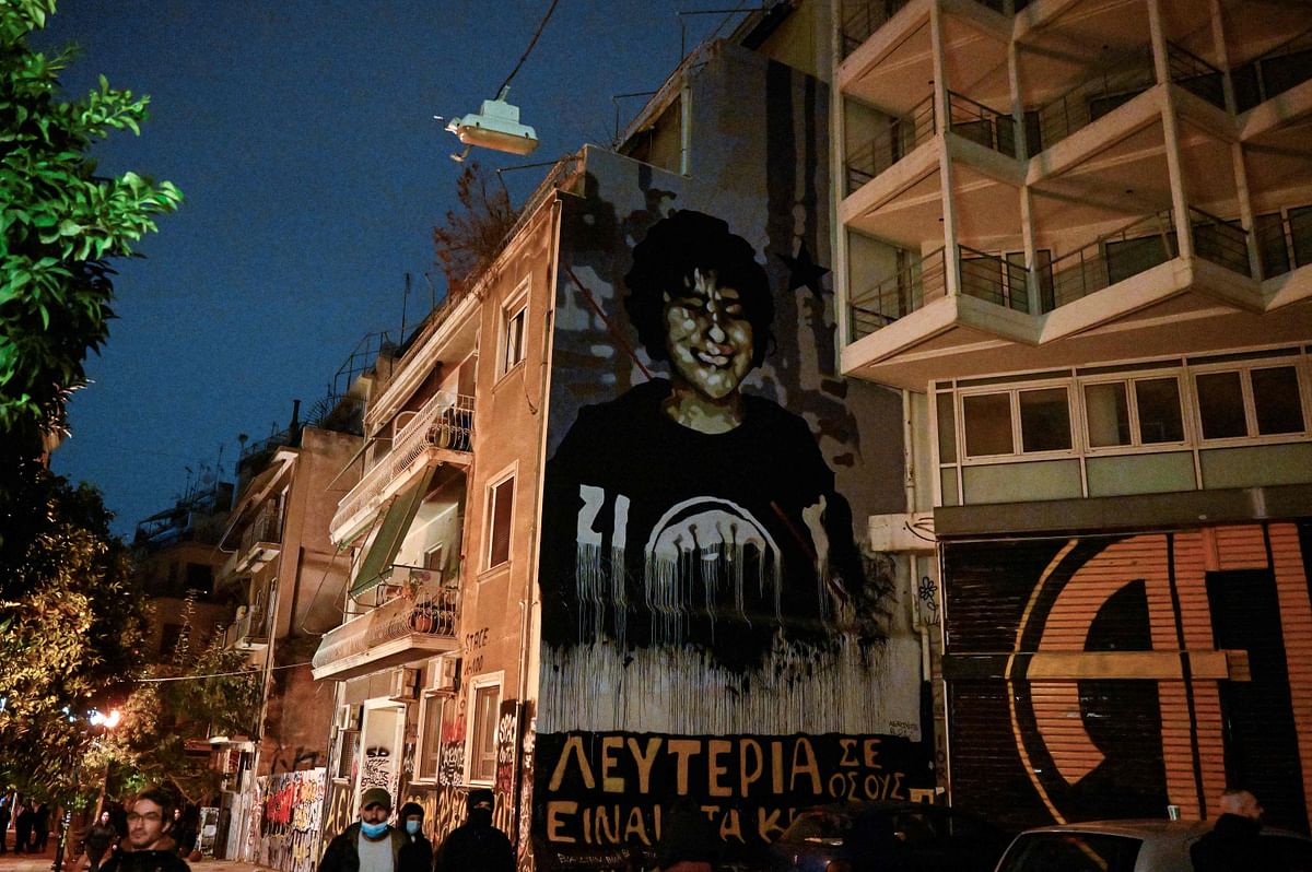 People walk by a mural depicting the 15-year old Alexis Grigoropoulos, killed by police, after a rally, marking the 14th anniversary of the 2008 fatal police shooting of a teenager in central Athens. Credit: AFP Photo