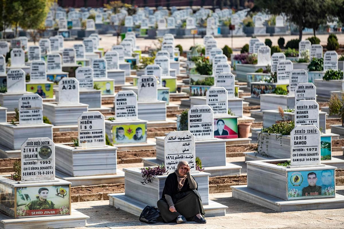 A mourner sits at a cemetary near the funeral procession of a fighter of the Kurdish People's Protection Units (YPG), in Syria's northeastern Kurdish-majority city of Qamishli. Credit: AFP Photo