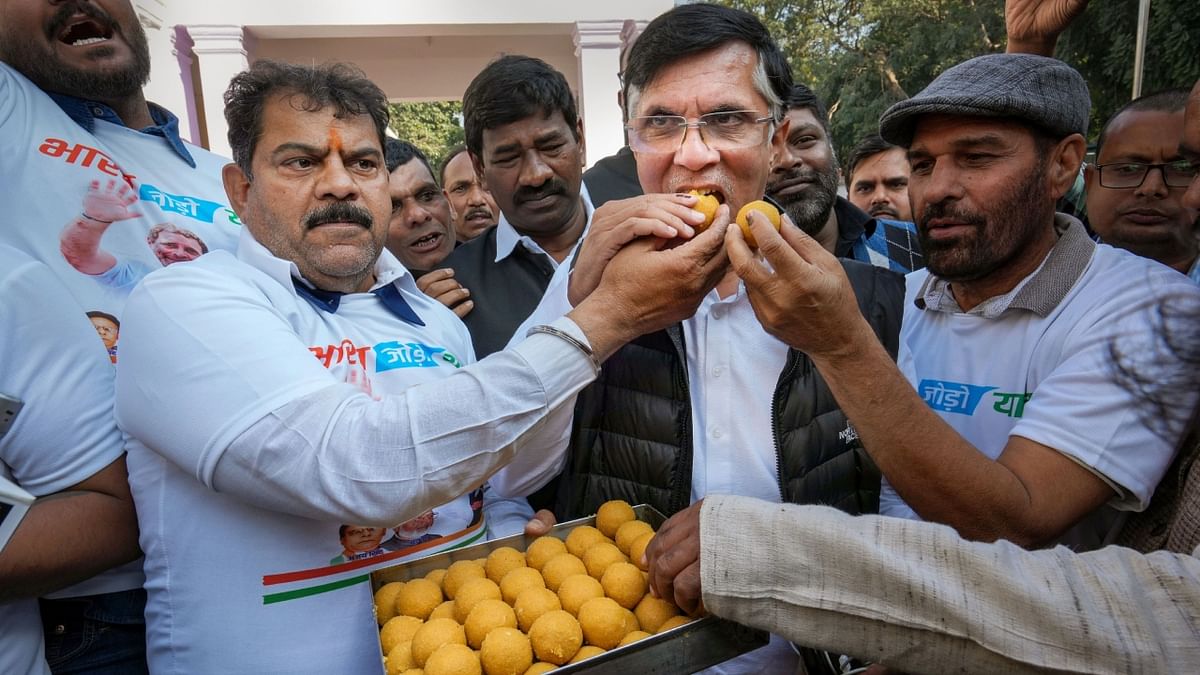 Congress supporters offer sweets to party leader Pawan Khera celebrating the party's lead in Himachal Pradesh Assembly elections, at AICC headquarters in New Delhi. Credit: PTI Photo