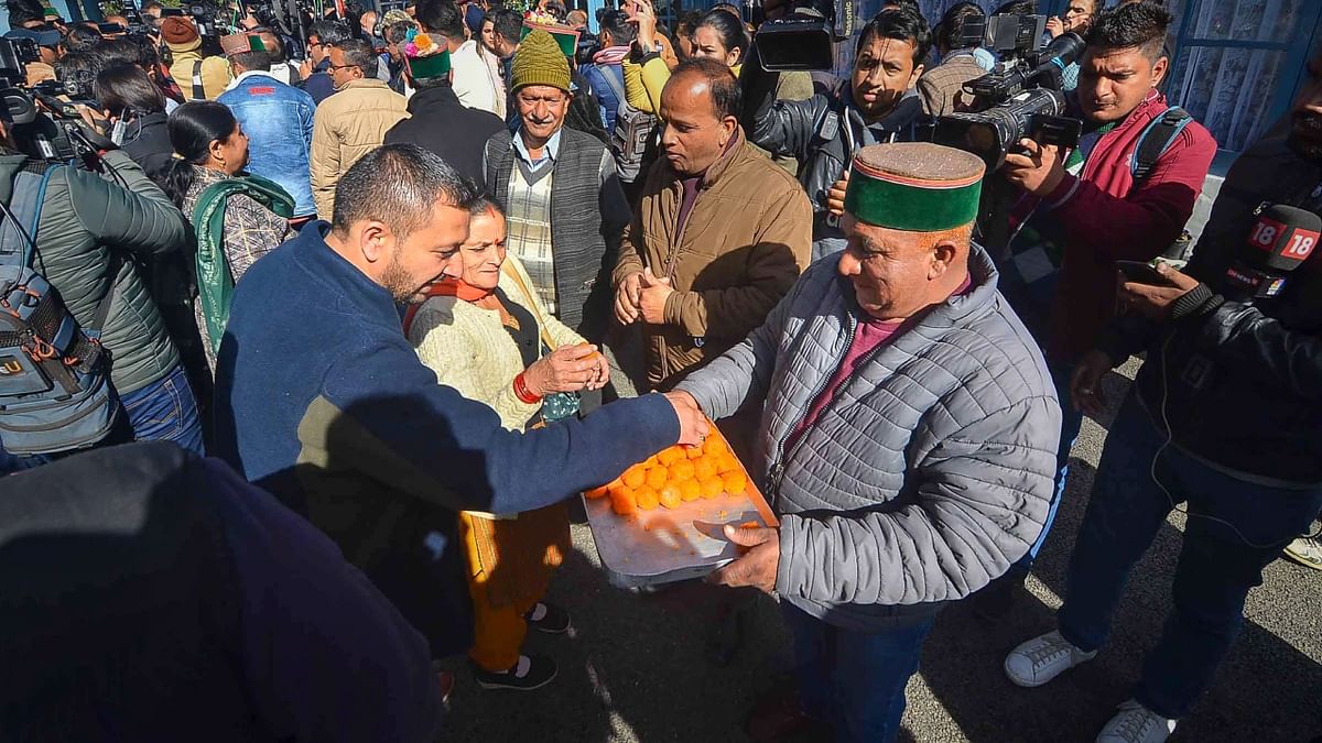 Congress workers distribute sweets as they celebrate the party's lead in the Himachal Pradesh Assembly elections, in Shimla. Credit: PTI Photo