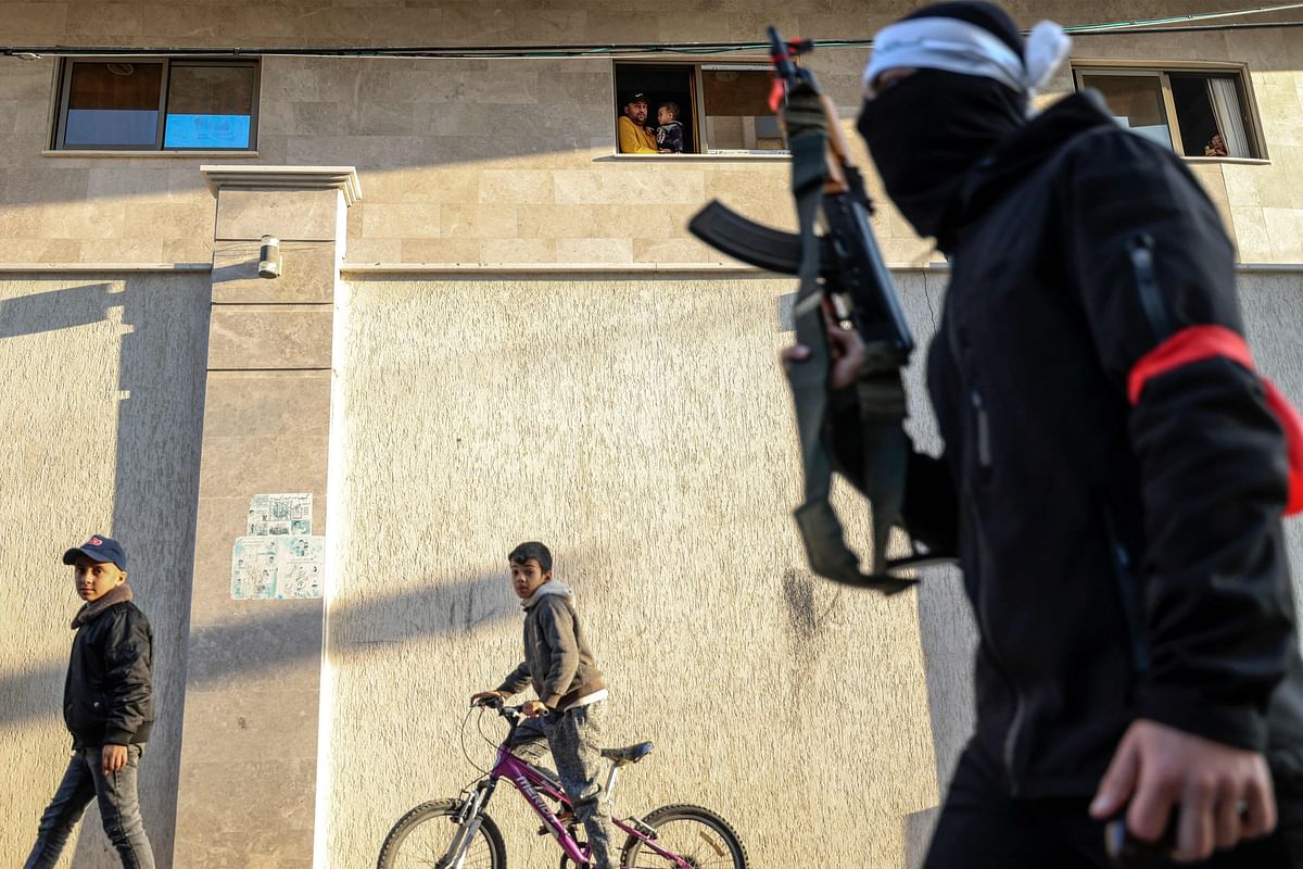 Palestinians look on Hamas militants march in support of Nablus based Lion's Den armed group (Areen Al-Asood), a loose coalition of fighters not aligned with established Palestinian factions, in Gaza City on December 10, 2022. Credit: AFP Photo