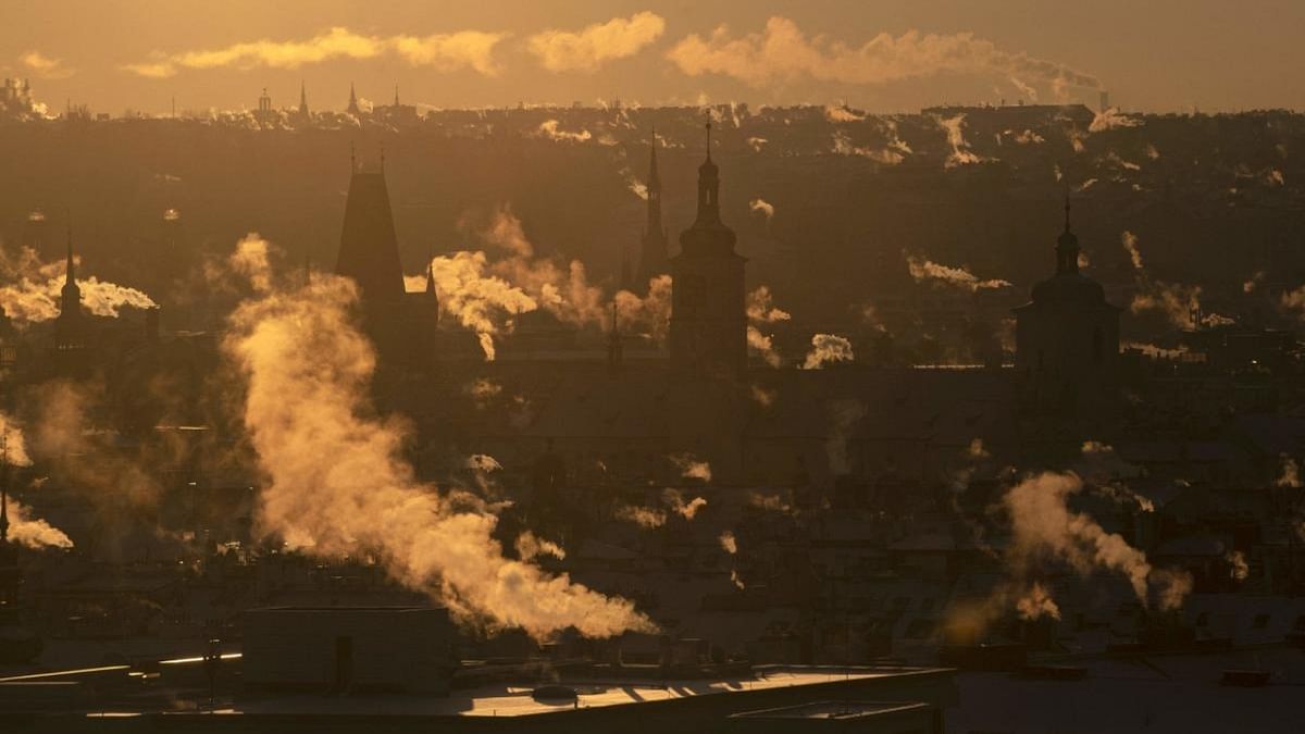 Smoke comes out of the chimneys from the rooftops of houses in central Prague during the sunrise. Credit: AFP Photo