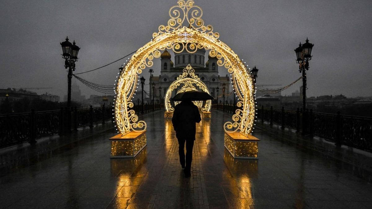 A pedestrian holds an umbrella as he walks past Christmas decorations during rainy weather near the Cathedral of Christ the Saviour in central Moscow. Credit: AFP Photo