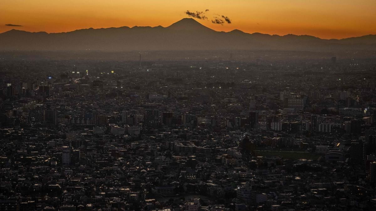 Mount Fuji (back) is seen behind the city skyline at dusk from Tokyo Metropolitan Government Building Observatories in Tokyo. Credit: AFP Photo