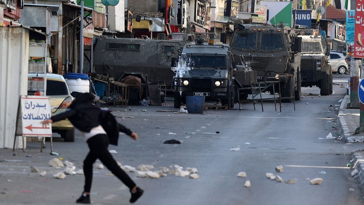 Palestinian protesters hurl rocks at members of the Israeli army during a reported raid in the Palestinian Askar refugee camp near Nablus in the occupied West Bank, on December 18, 2022. Credit: AFP Photo