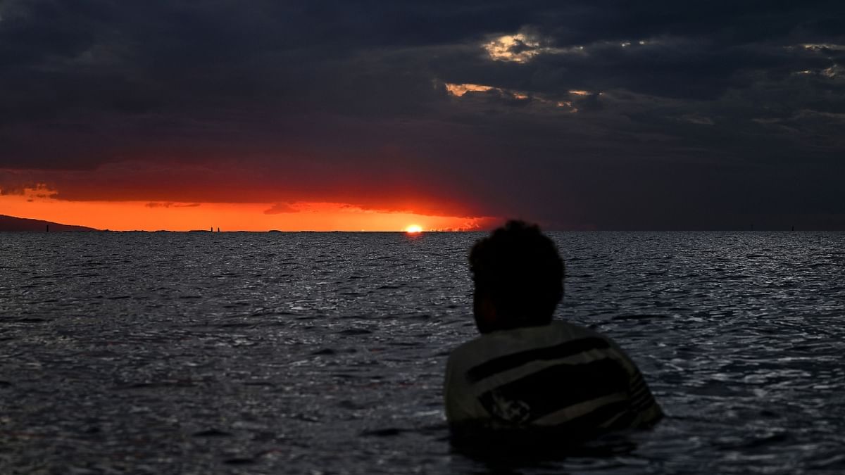 A woman watches the sunset during the low tide in Fiji’s capital city Suva on December 19, 2022. Credit: AFP Photo