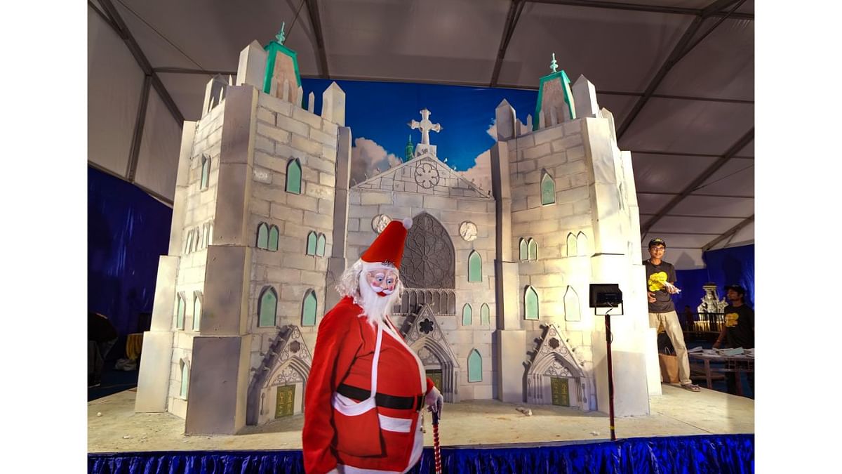 A man dressed as Santa Claus walks past a cake model of The Cathedral Basilica during the press conference of 48th annual Cake Show, in Bengaluru. Credit: PTI Photo