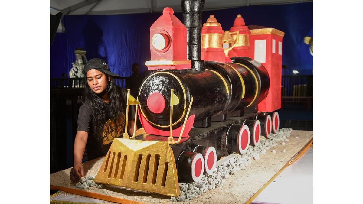 A baker is seen giving a final touch to a Engine shaped cake at the 48th Annual Cake Show at St. Josphs School Grounds in Bengaluru. Credit: BH Shivakumar/DH Photo