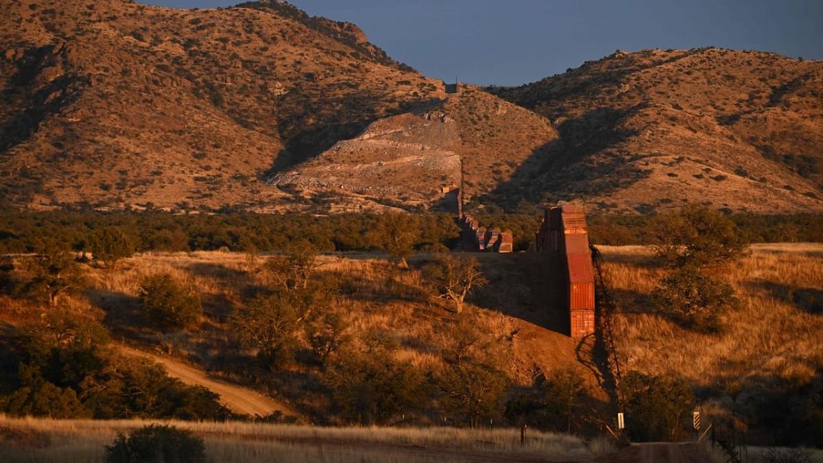 A large gap on steep terrain is seen where the steel bollard-style wall ends before the beginning of another border wall constructed of shipping containers and topped with concertina wire, built on federal land by Republican governor Doug Ducey, stands along the US-Mexico border in the Coronado National Forest near Hereford, Arizona. Credit: AFP Photo