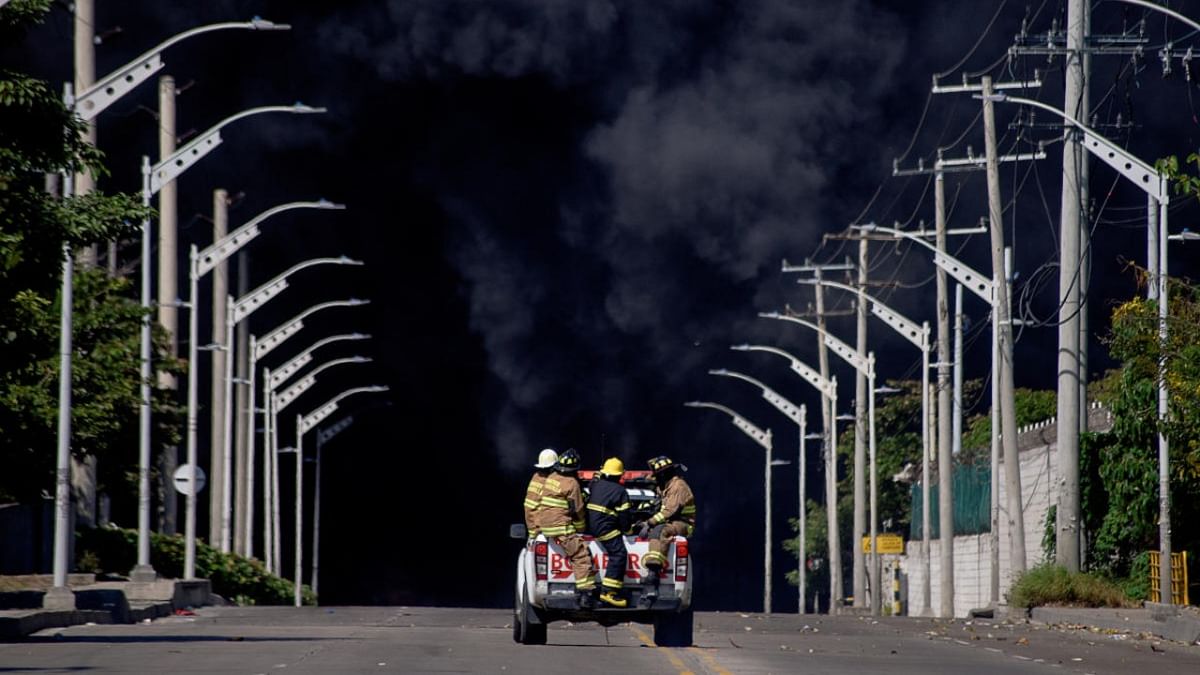 Firefighters are transported in a car as black smoke rises during a fire in a hydrocarbon storage area of the Bravo Petroleum company in Barranquilla, Colombia. Credit: Reuters photo