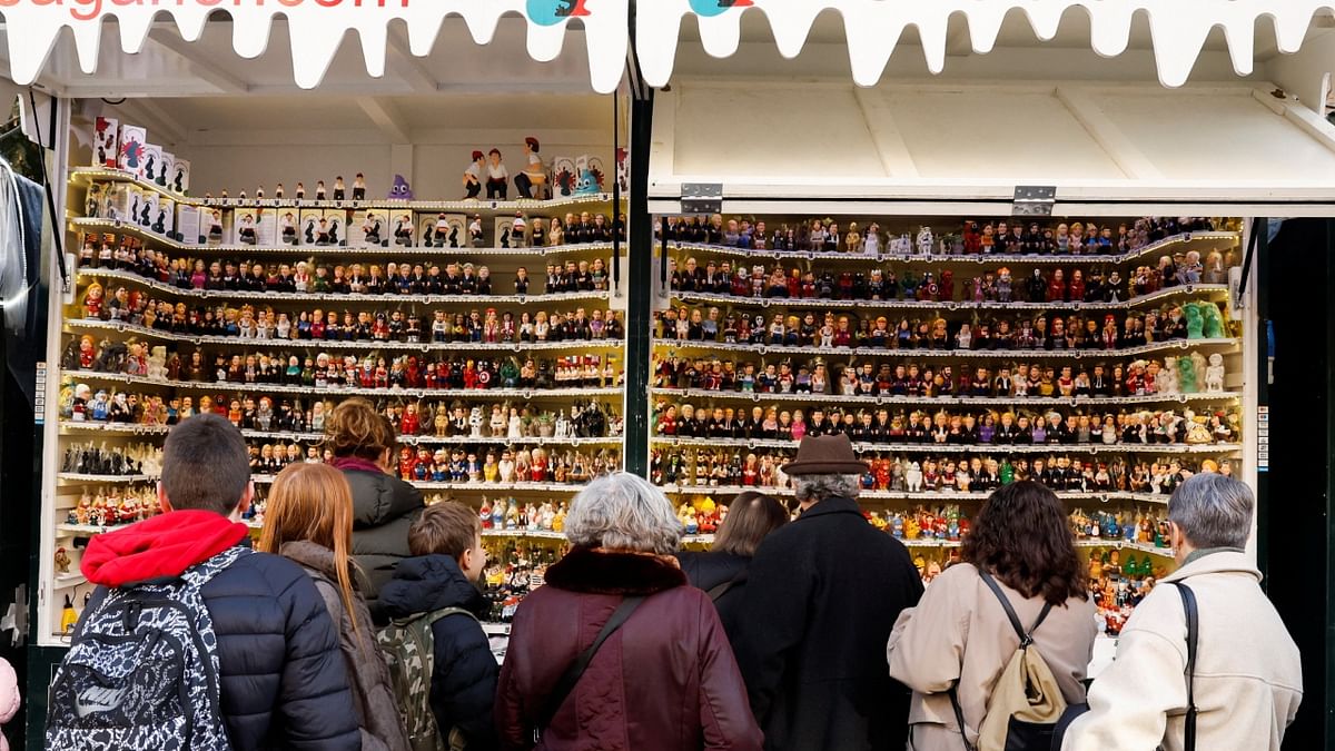 People look at clay 'caganers' figures, which symbolise defecation and fertilisation of the earth, and are believed to bring prosperity and luck for the coming year, in a stall at the Santa Llucia Christmas market in Barcelona, Spain. Credit: Reuters Photo