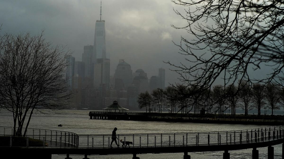 A woman walks her dog in a local park in Hoboken, New Jersey, while storm clouds pass by the One World Trade Center in New York. Credit: Reuters photo