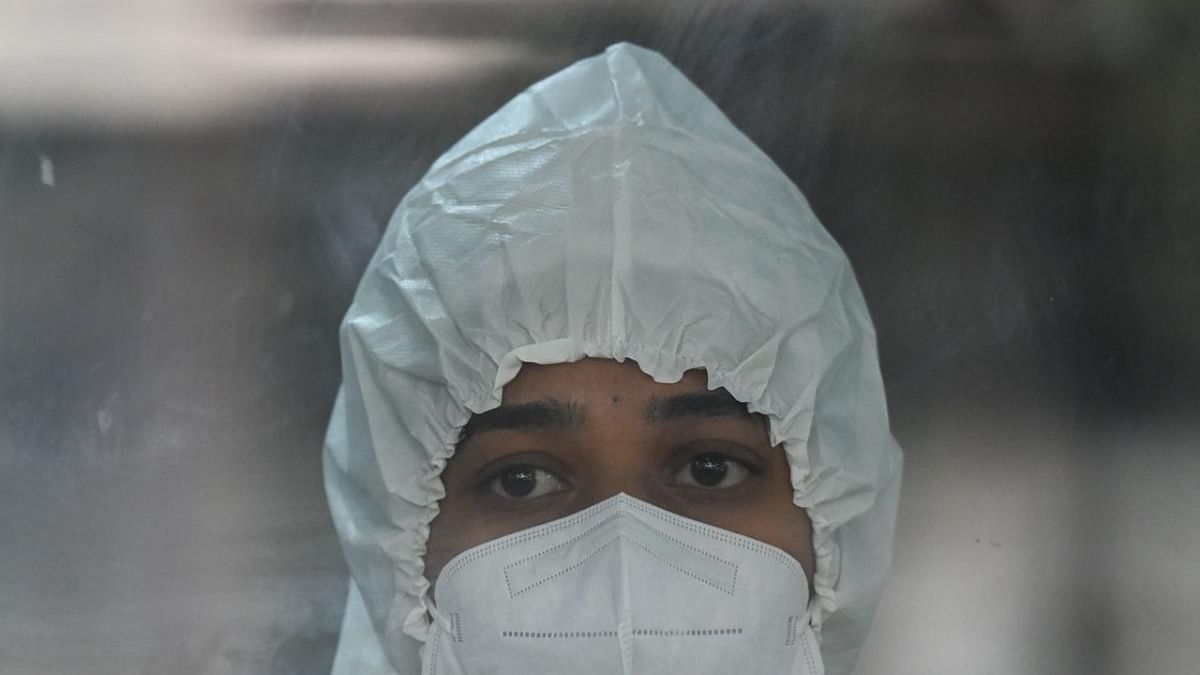 A health worker wearing personal protective equipment (PPE) stands inside a swab collection booth to check preparation of Covid-19 test facilities at a hospital in Mumbai on December 27, 2022. Credit: AFP Photo