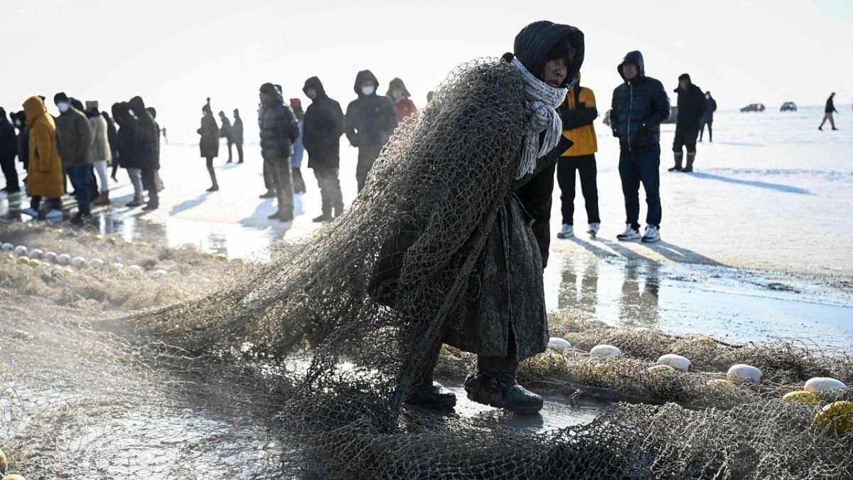 People watch as a fisherman carries a net placed under the ice to catch fish during the annual Chagan Lake Winter Fishing Festival in Songyuan, in northeastern China's Jilin province. Credit: AFP Photo